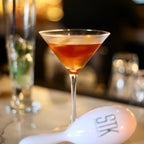 Cocktail in a martini glass on a bar counter with a blurred background