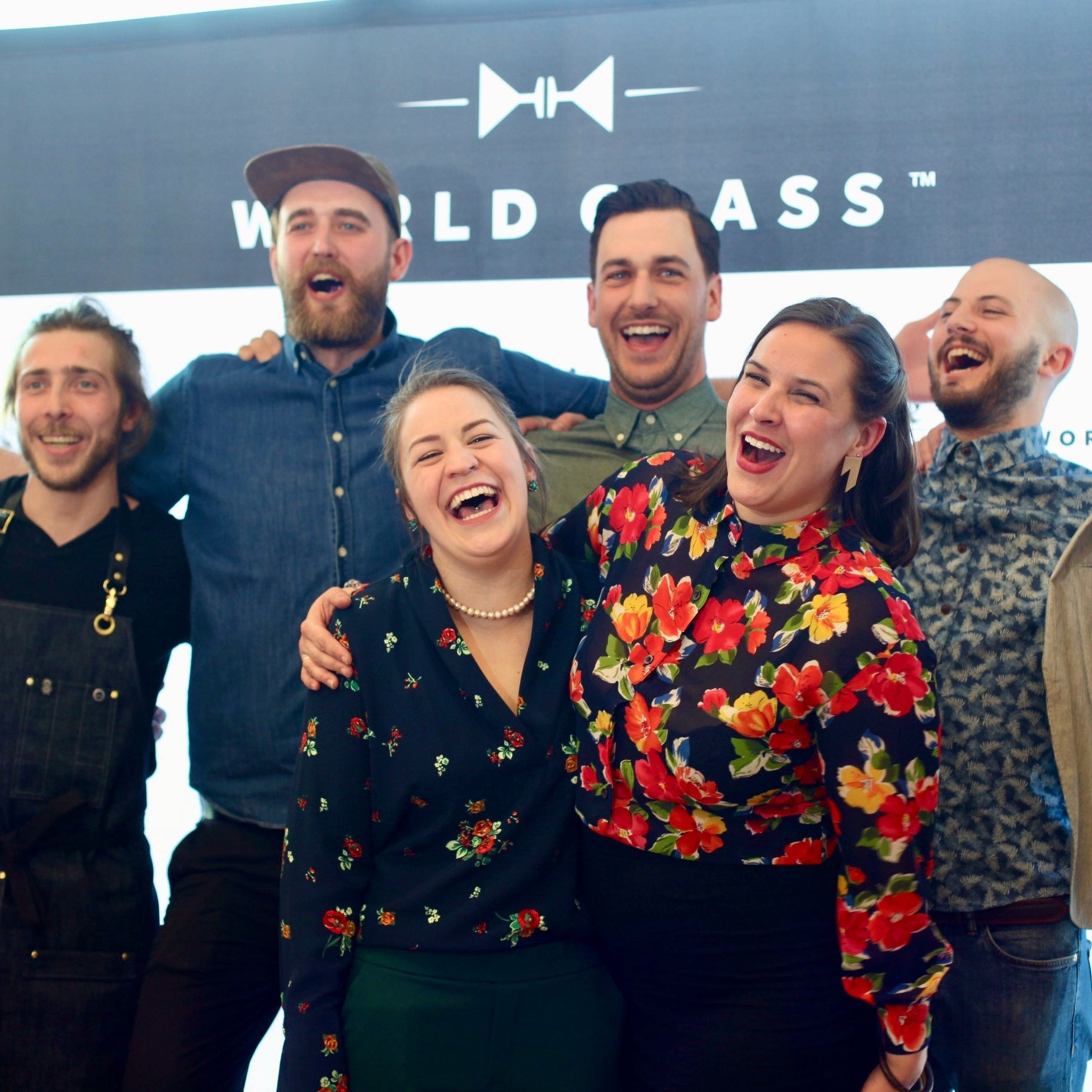 Group of people posing together in front of a World Class banner
