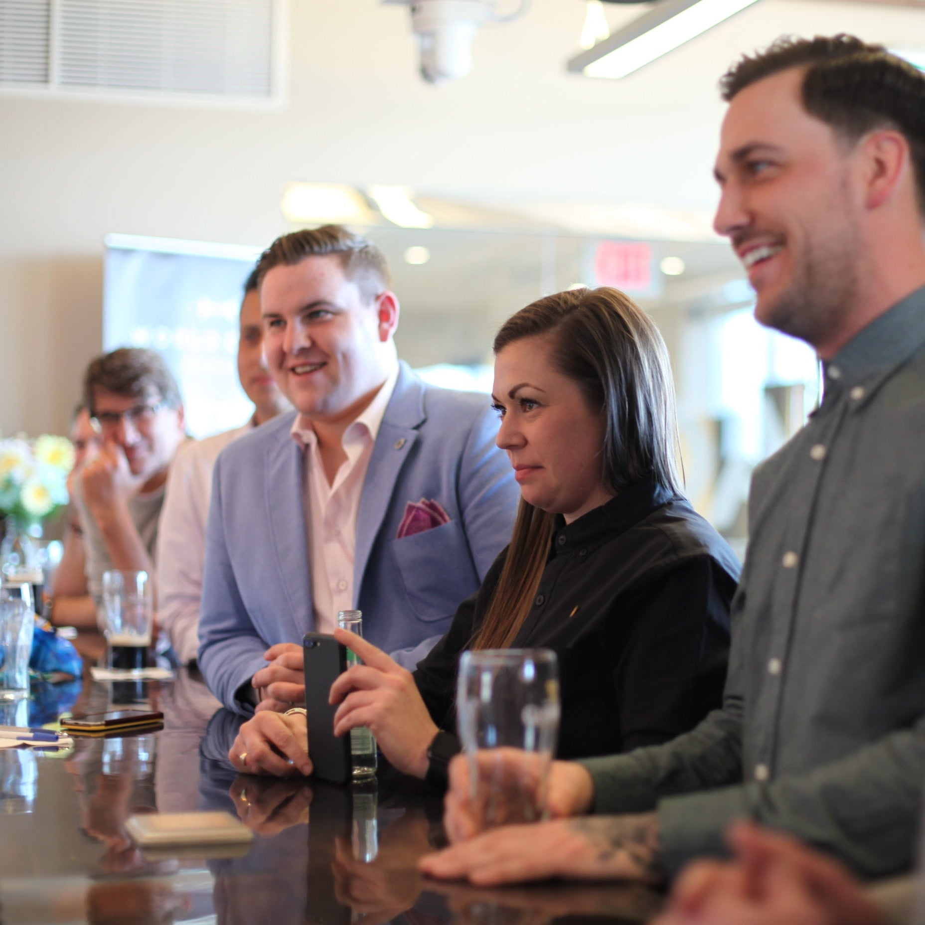 Group of people sitting at a bar, engaged in conversation.